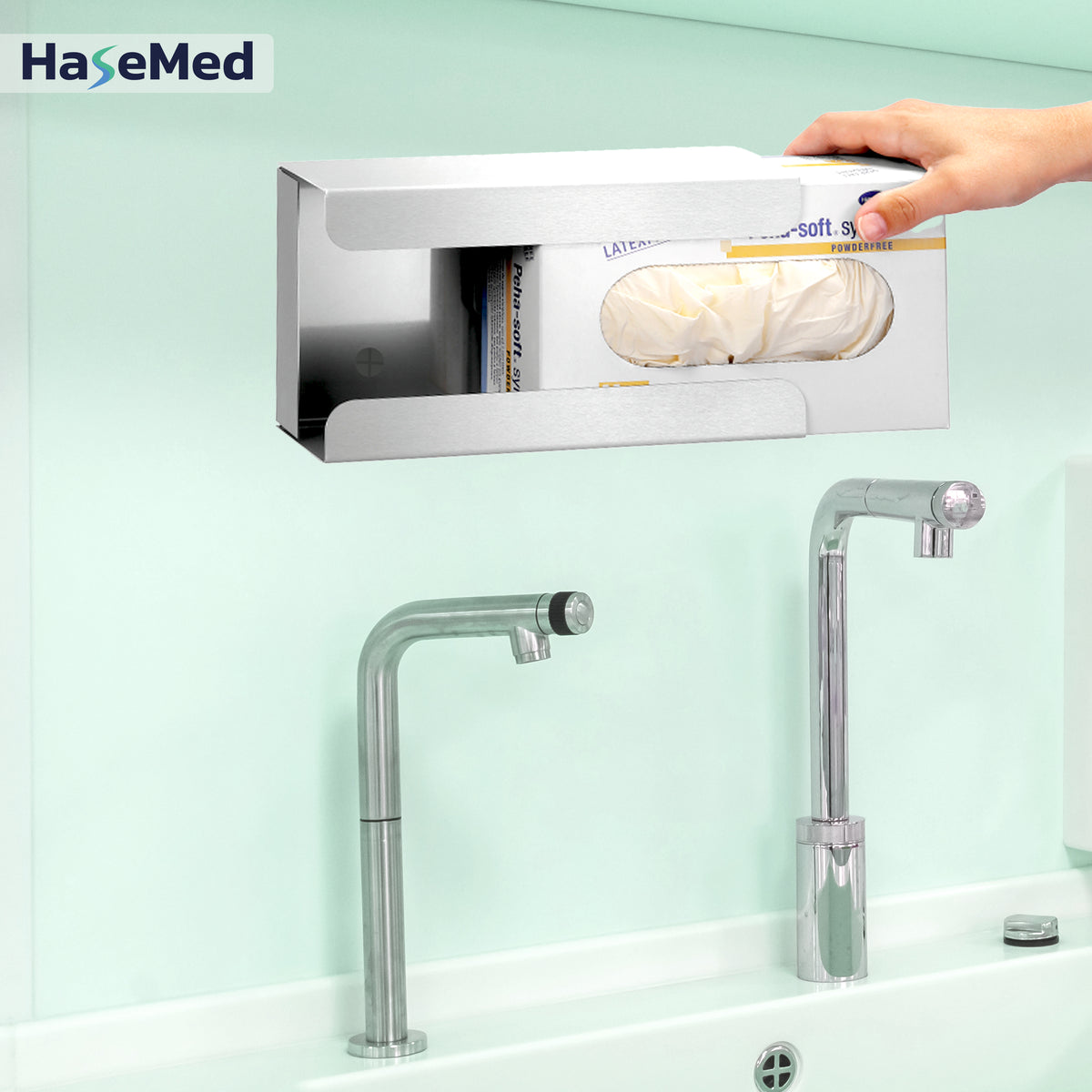 Supporto HaseMed HAS-30 in acciaio inox con molla per una scatola di guanti, mostrato durante l'inserimento di una scatola. Viene fornito un supporto. Guanti e scatole non inclusi.